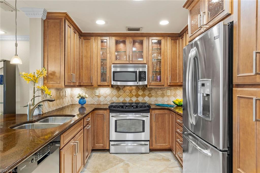 9101 Vanderbilt Drive, Unit 301 Naples, FL 34108 - Photo 6 of 28 a kitchen with stainless steel appliances granite countertop a refrigerator and a sink