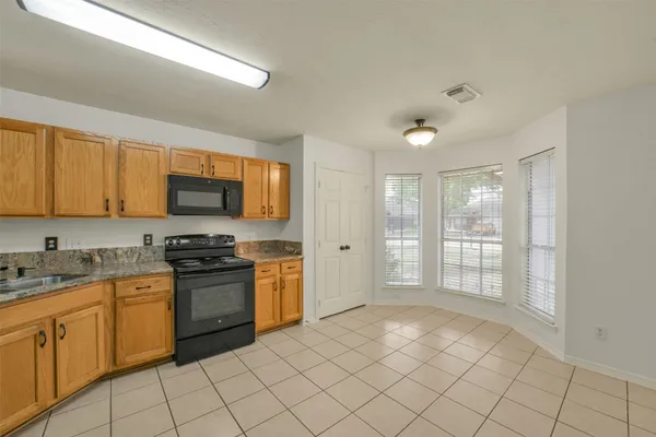 a kitchen with stainless steel appliances granite countertop a stove top oven a sink dishwasher and white cabinets with wooden floor