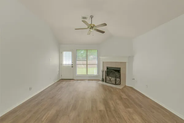 an empty room with chandelier fan and windows