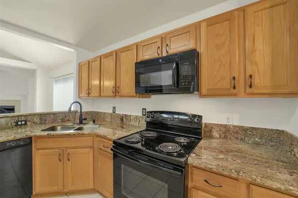 a kitchen with granite countertop a stove sink and cabinets
