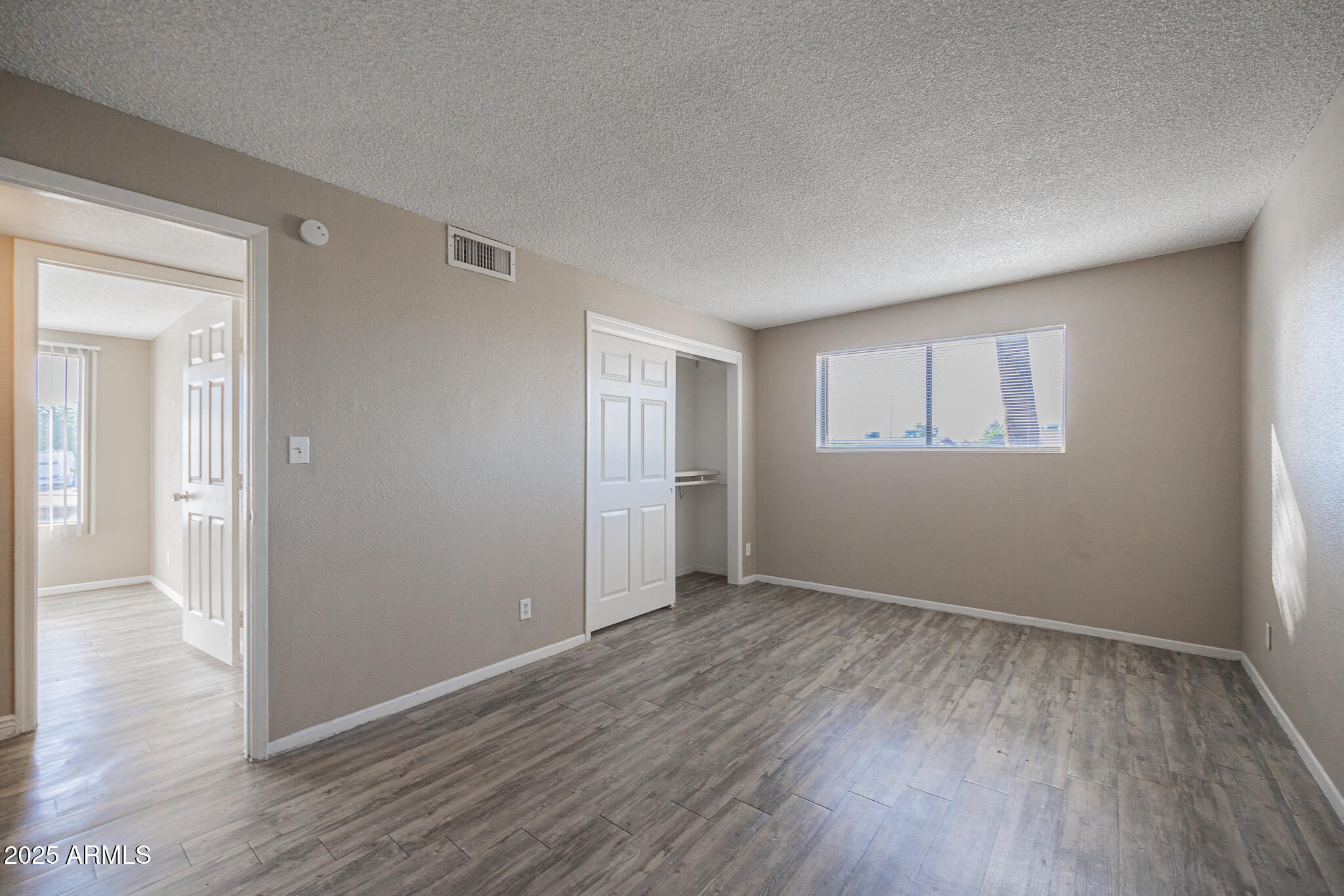 2411 West Hazelwood Street, Unit 278 Phoenix, AZ 85015 - Photo 12 of 20 a view of an empty room with wooden floor and a window