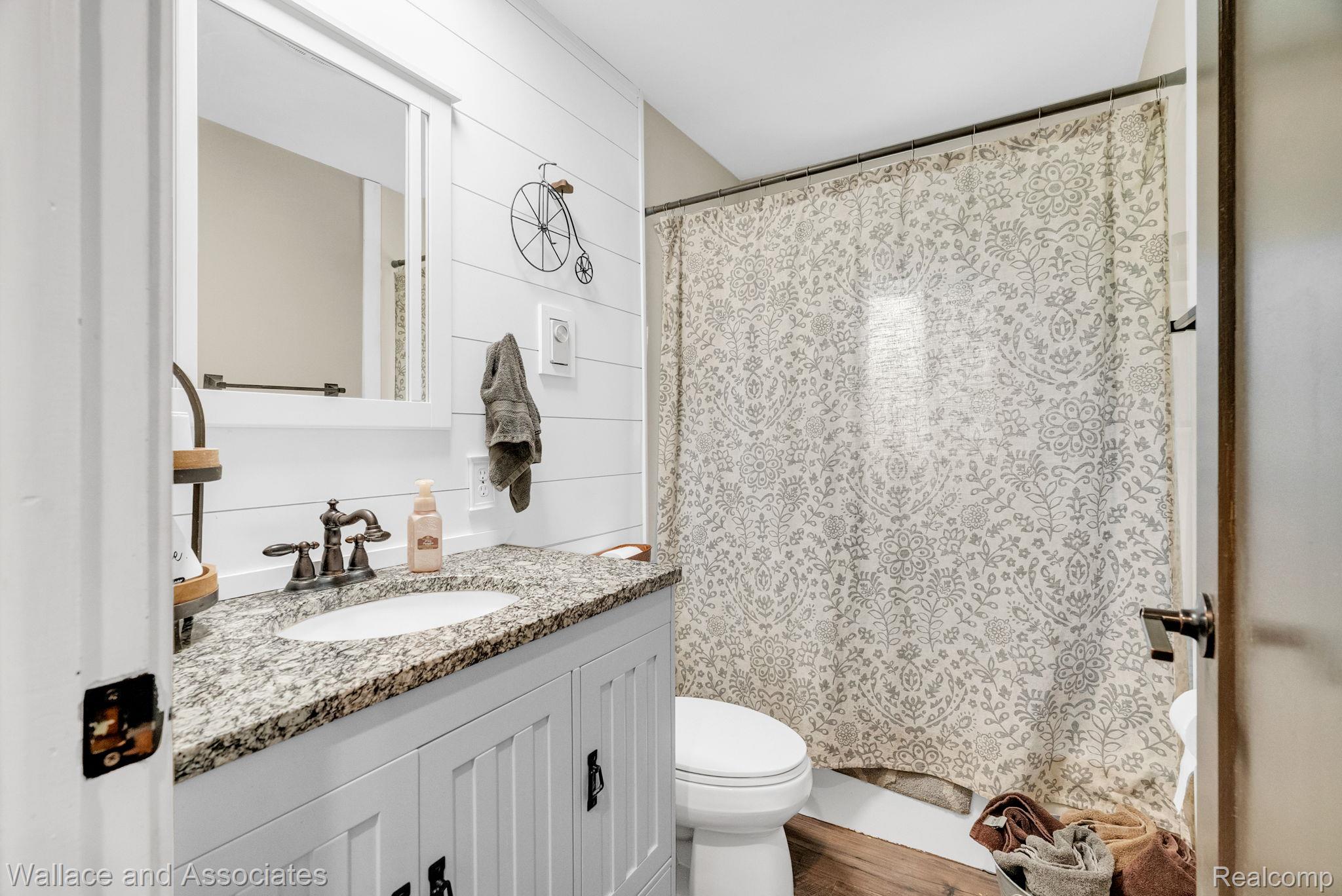 6616 Wellman Line Road Croswell, MI 48422 - Photo 28 of 47 Full bathroom featuring a shower with shower curtain, vanity, and wood walls