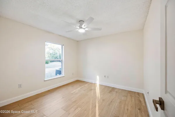 an empty room with wooden floor and windows
