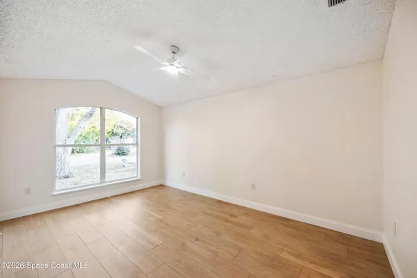 an empty room with wooden floor and windows
