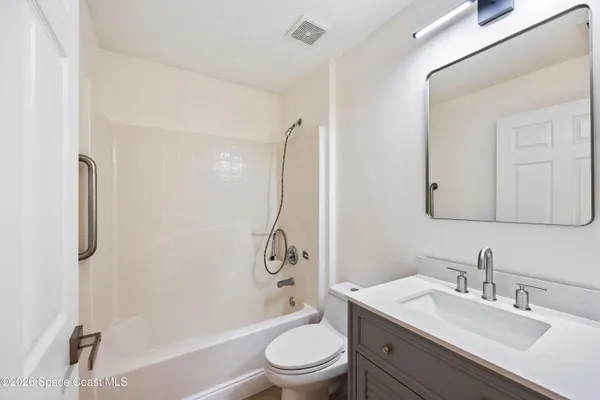 a bathroom with a granite countertop sink toilet a mirror and shower