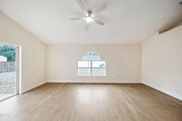 an empty room with wooden floor and windows
