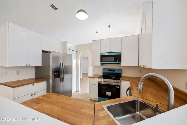 a kitchen with stainless steel appliances kitchen island granite countertop a refrigerator stove and sink with wooden cabinets