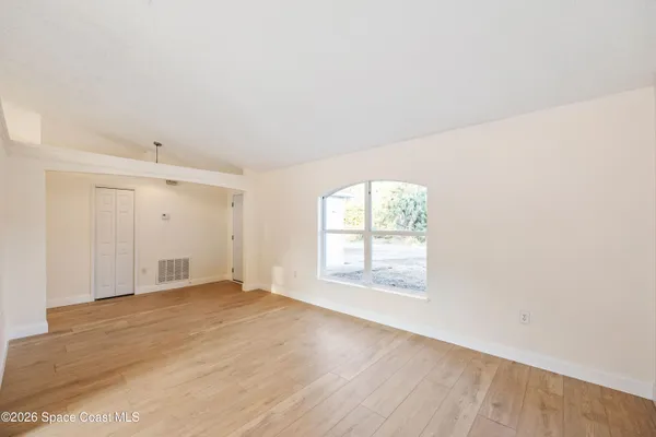 an empty room with wooden floor and windows