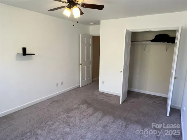 an empty room with closet and a ceiling fan