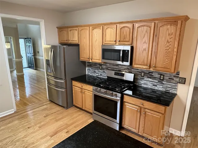 a kitchen with granite countertop a refrigerator stove and microwave