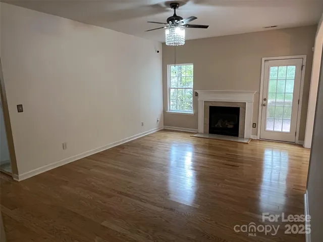 an empty room with wooden floor fireplace and windows