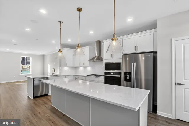 a kitchen with stainless steel appliances granite countertop a refrigerator a sink a stove and a wooden floor