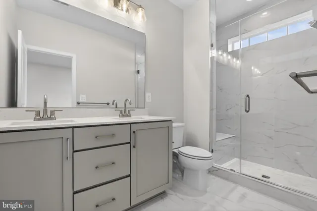 a bathroom with a double vanity sink toilet and shower