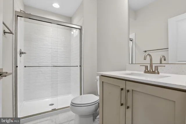 a bathroom with a shower sink vanity and toilet