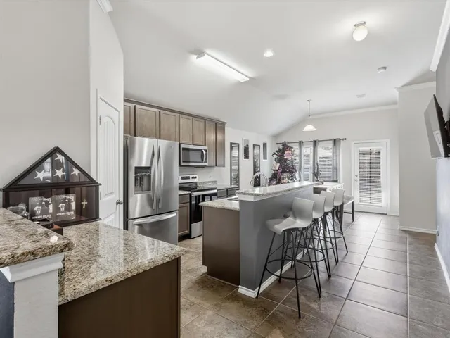 a kitchen with stainless steel appliances granite countertop a refrigerator a stove a sink a dining table and chairs