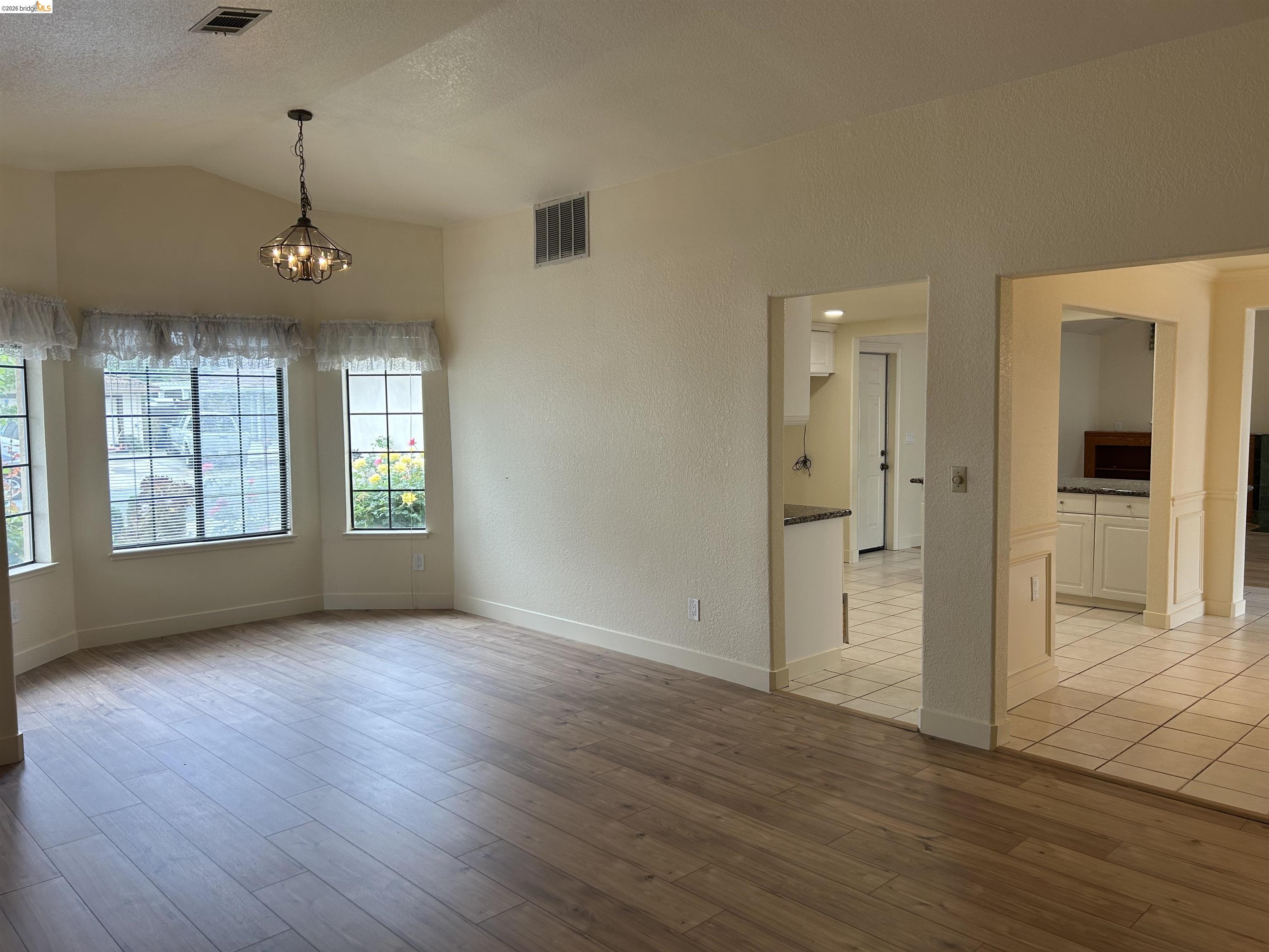 2632 Point Lobos Court Antioch, CA 94531 - Photo 5 of 27 Empty room with hanging lights, light wood-type flooring, and a textured wall
