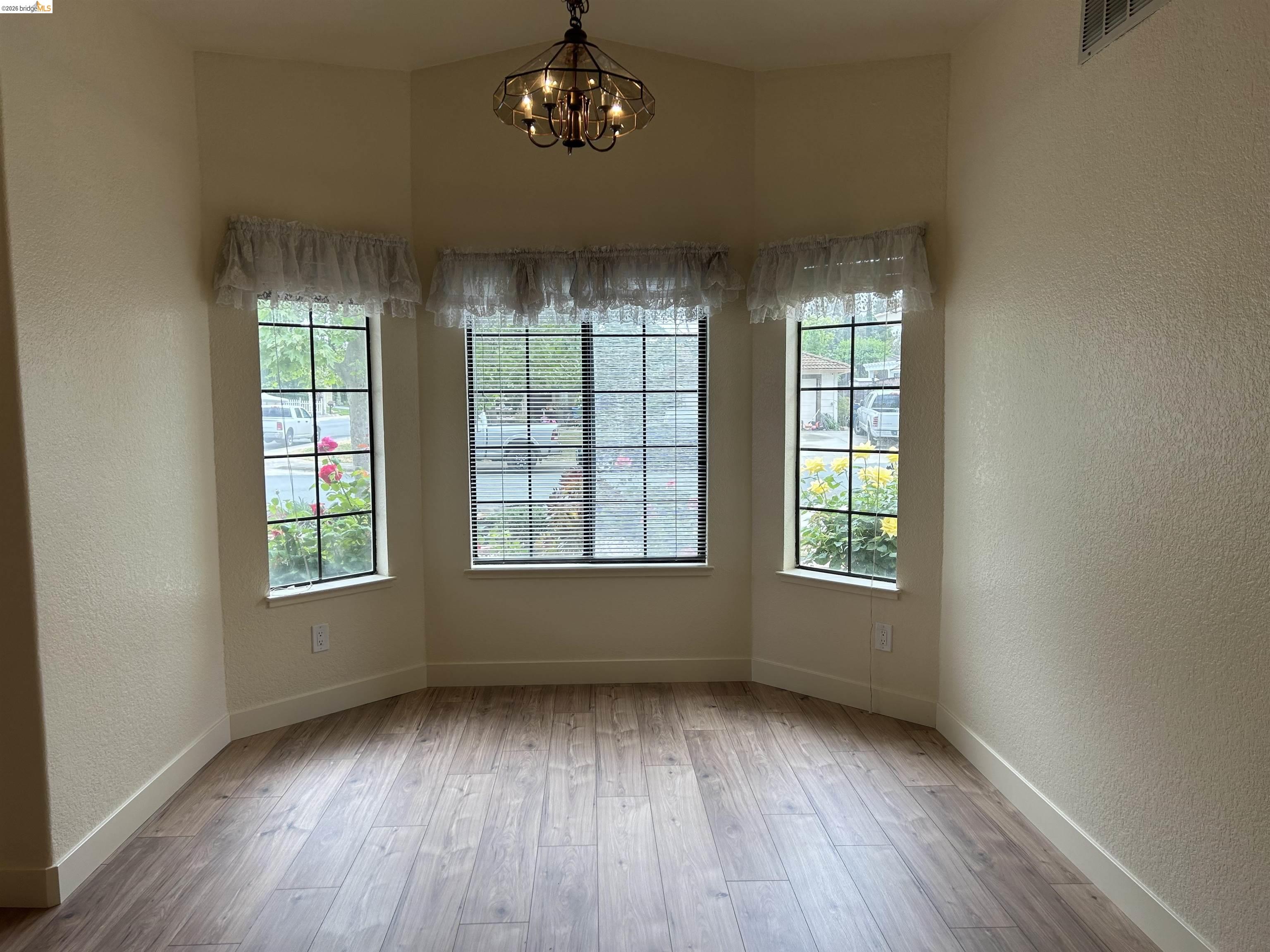 2632 Point Lobos Court Antioch, CA 94531 - Photo 6 of 27 Empty room featuring a textured wall, suspended lighting, and light wood-style flooring