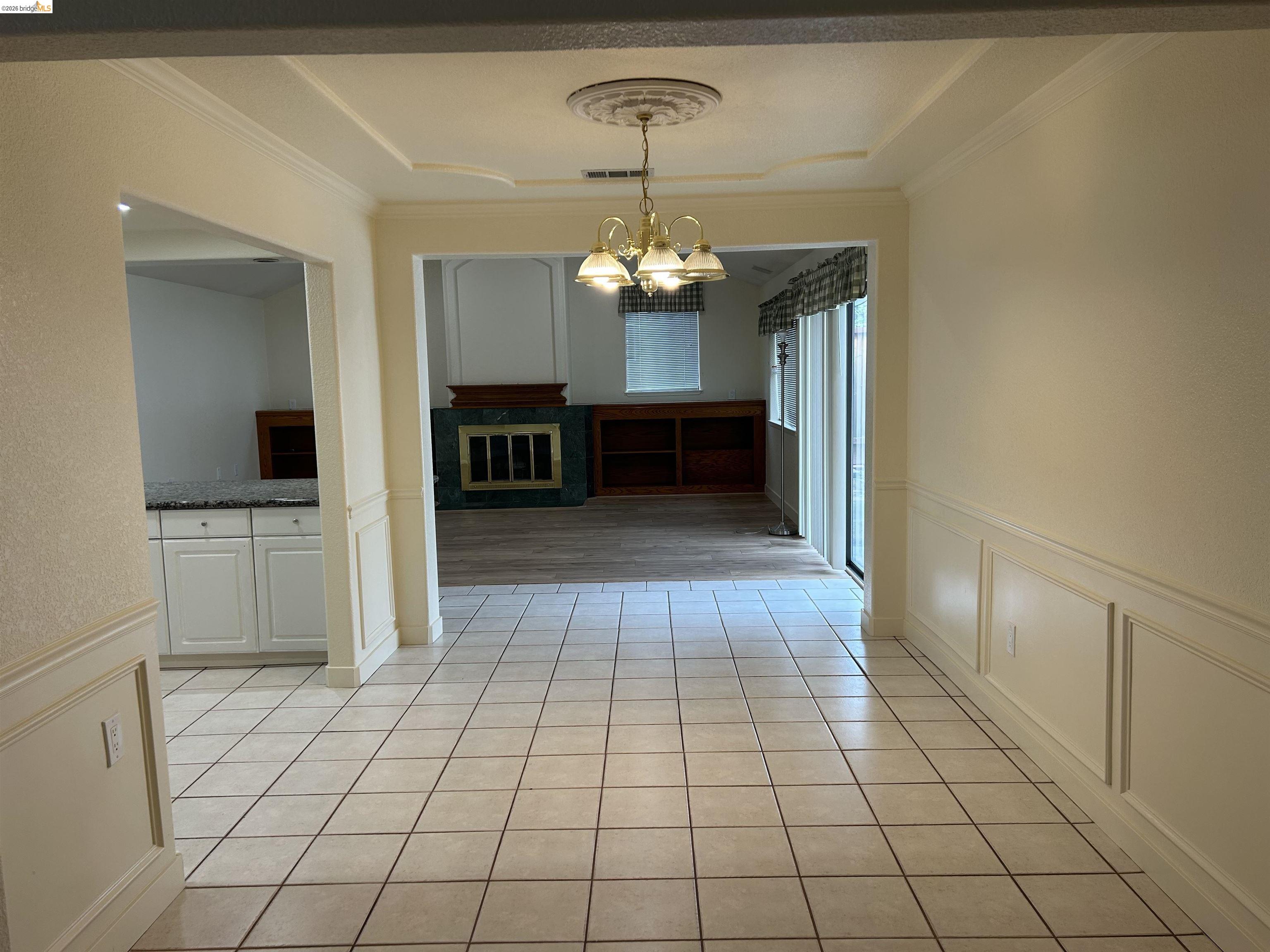 2632 Point Lobos Court Antioch, CA 94531 - Photo 7 of 27 Unfurnished dining area featuring a decorative wall, a wainscoted wall, crown molding, a chandelier, and light tile patterned floors