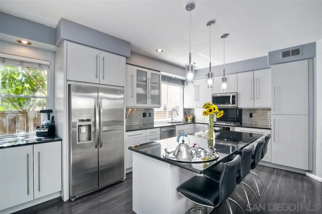 11564 Village Ridge Road San Diego, CA 92131 - Photo 11 of 25 a kitchen with stainless steel appliances a dining table chairs and refrigerator