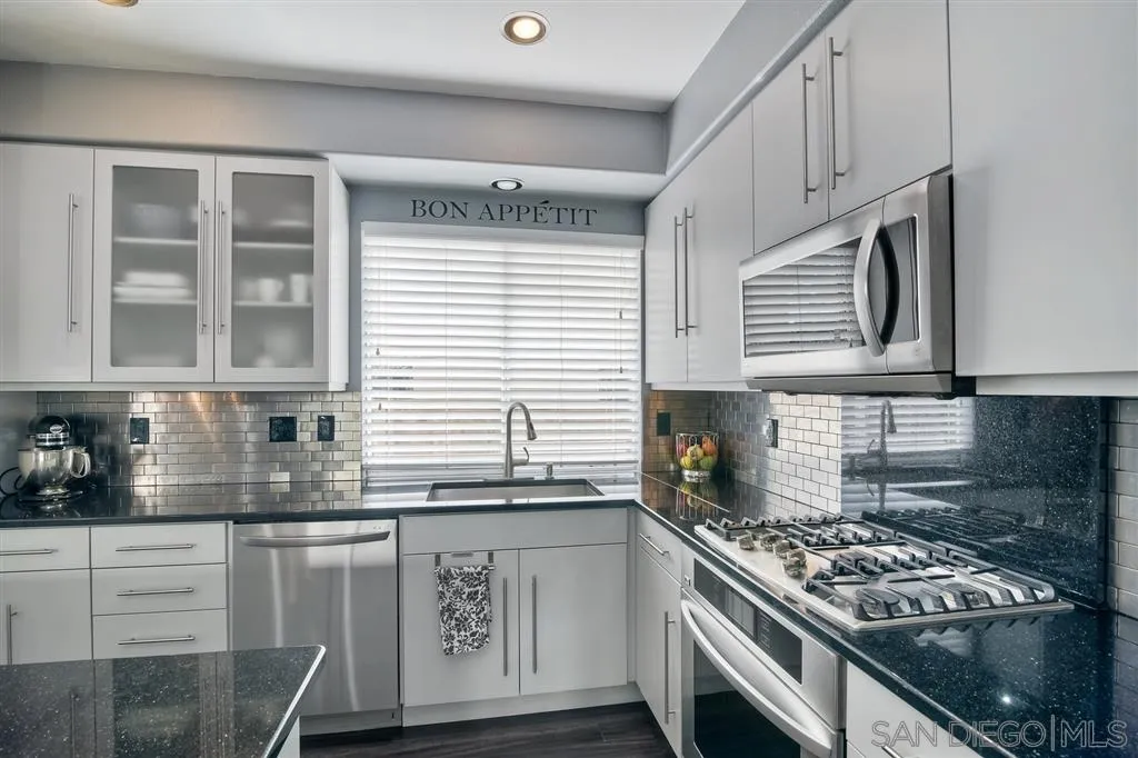 11564 Village Ridge Road San Diego, CA 92131 - Photo 12 of 25 a kitchen with stainless steel appliances granite countertop a stove and a white cabinets