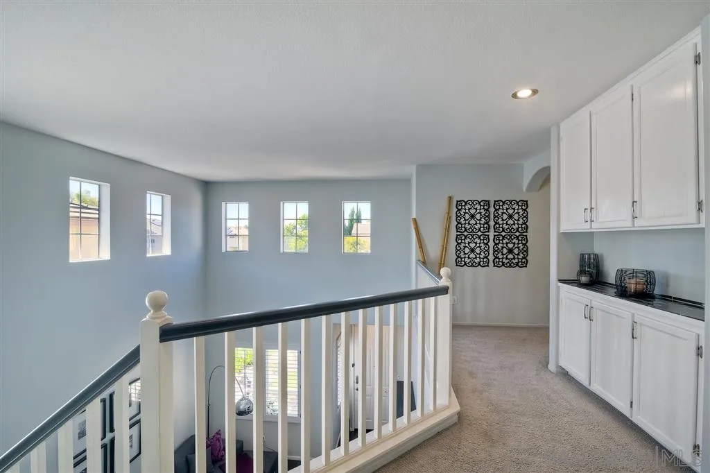 11564 Village Ridge Road San Diego, CA 92131 - Photo 13 of 25 a view of a hallway to kitchen with wooden floor and stairs