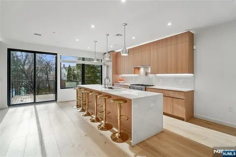 a kitchen with stainless steel appliances granite countertop a stove a sink dishwasher and a refrigerator with wooden floor