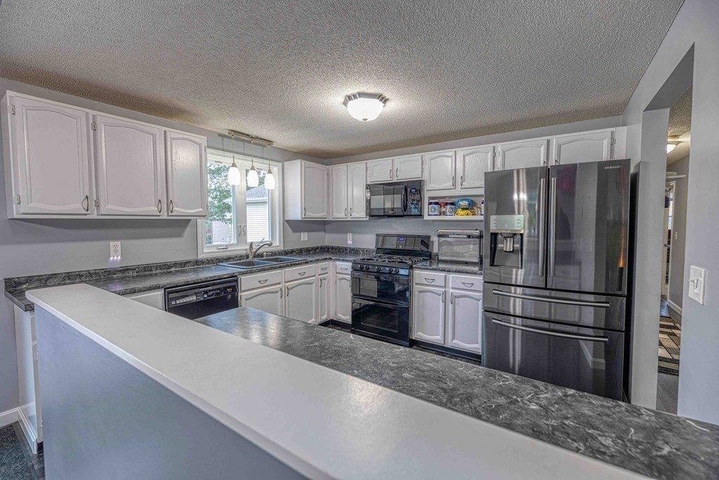 583 Wood Street Fall River, MA 02721 - Photo 12 of 32 a kitchen with a refrigerator a microwave a sink and cabinets
