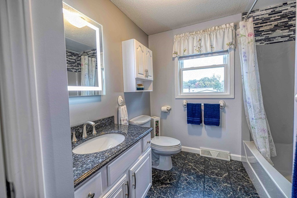 583 Wood Street Fall River, MA 02721 - Photo 16 of 32 a bathroom with a granite countertop sink a toilet a mirror and shower