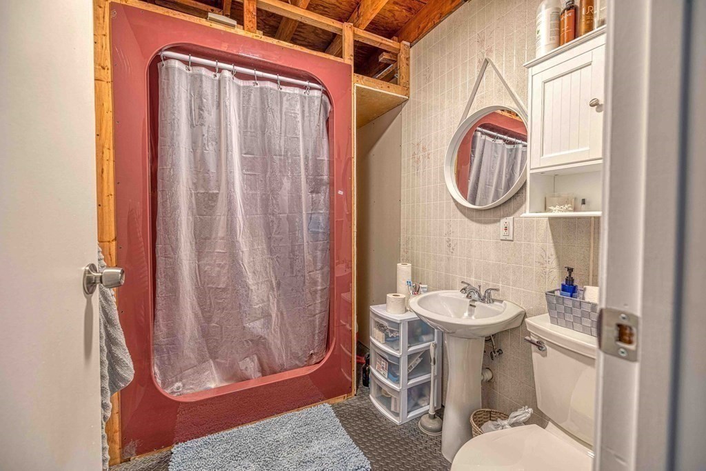 583 Wood Street Fall River, MA 02721 - Photo 21 of 32 a bathroom with a sink a toilet and shower curtain