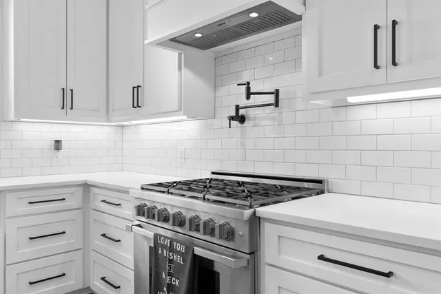 a kitchen with granite countertop a stove and white cabinets