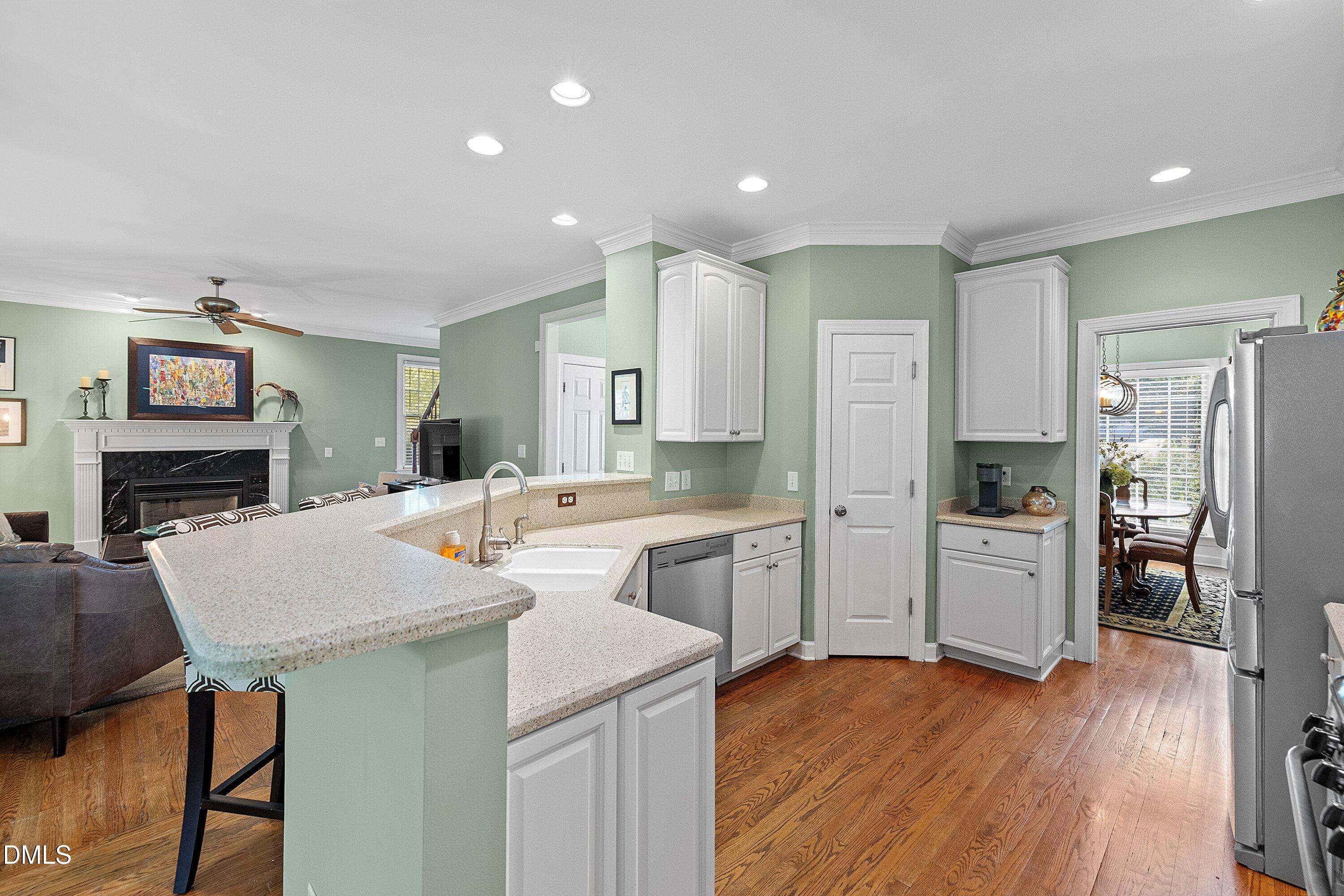 3914 Sterling Ridge Lane Durham, NC 27707 - Photo 23 of 66 Kitchen featuring white cabinetry, light-toned countertops, a stainless steel dishwasher, and wood-finish flooring