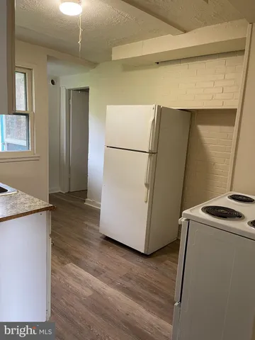 a view of a refrigerator in kitchen and an empty room