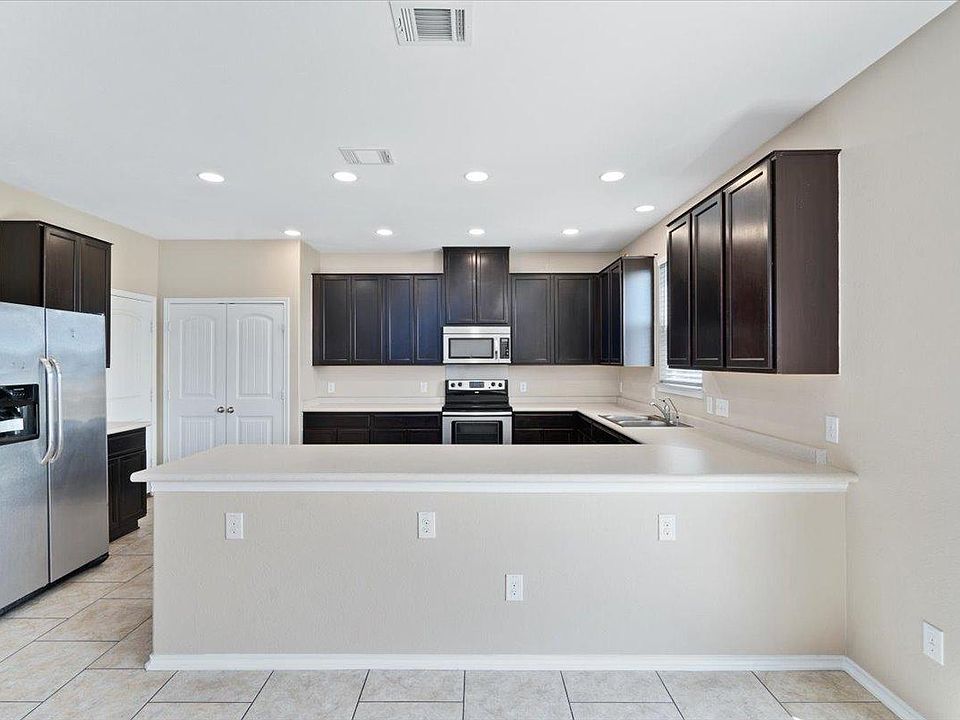 904 Lonesome Lilly Way Pflugerville, TX 78660 - Photo 5 of 34 The kitchen features dark wood cabinetry, stainless steel appliances, and a breakfast bar with ample counter space