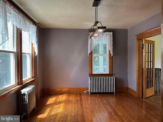 a view of empty room with wooden floor and windows