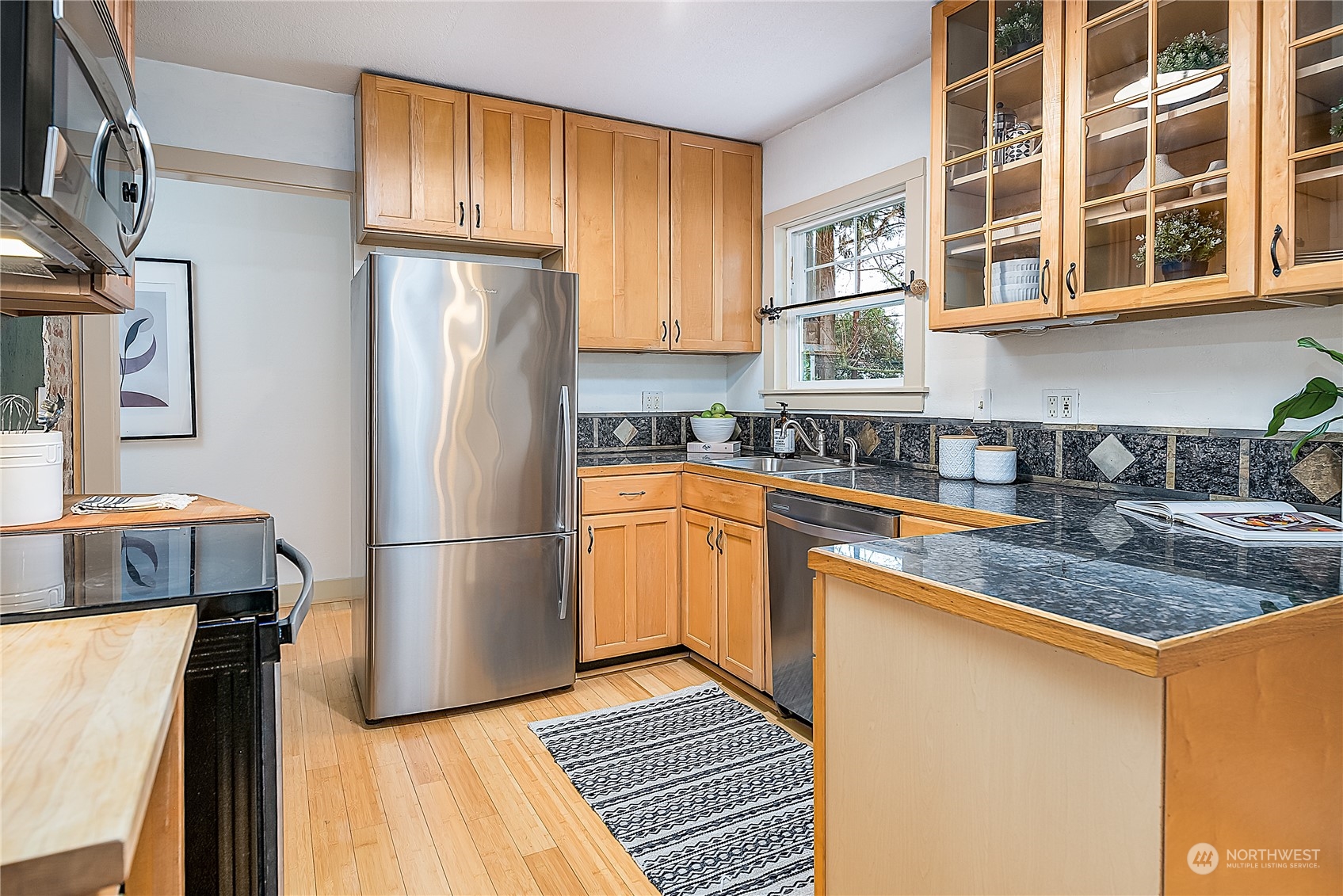 4100 Southwest Raymond Street Seattle, WA 98136 - Photo 9 of 23 a kitchen with stainless steel appliances granite countertop a refrigerator a sink dishwasher a stove with wooden cabinets and floor