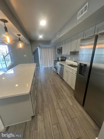 a kitchen with stainless steel appliances a refrigerator a sink dishwasher a stove and white countertops with wooden floor