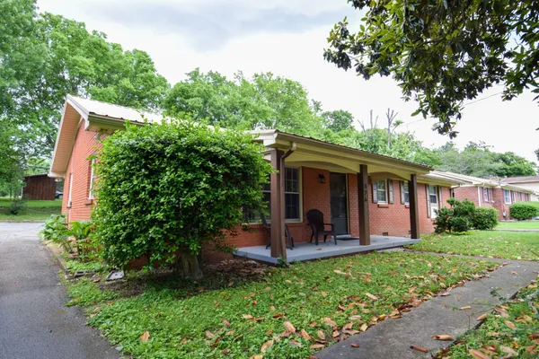 a view of a house with garden and a tree
