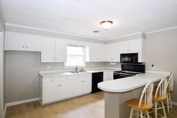 a kitchen that has a sink a stove and chairs