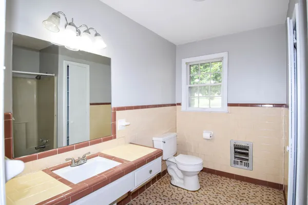 a bathroom with a granite countertop sink a toilet and a mirror