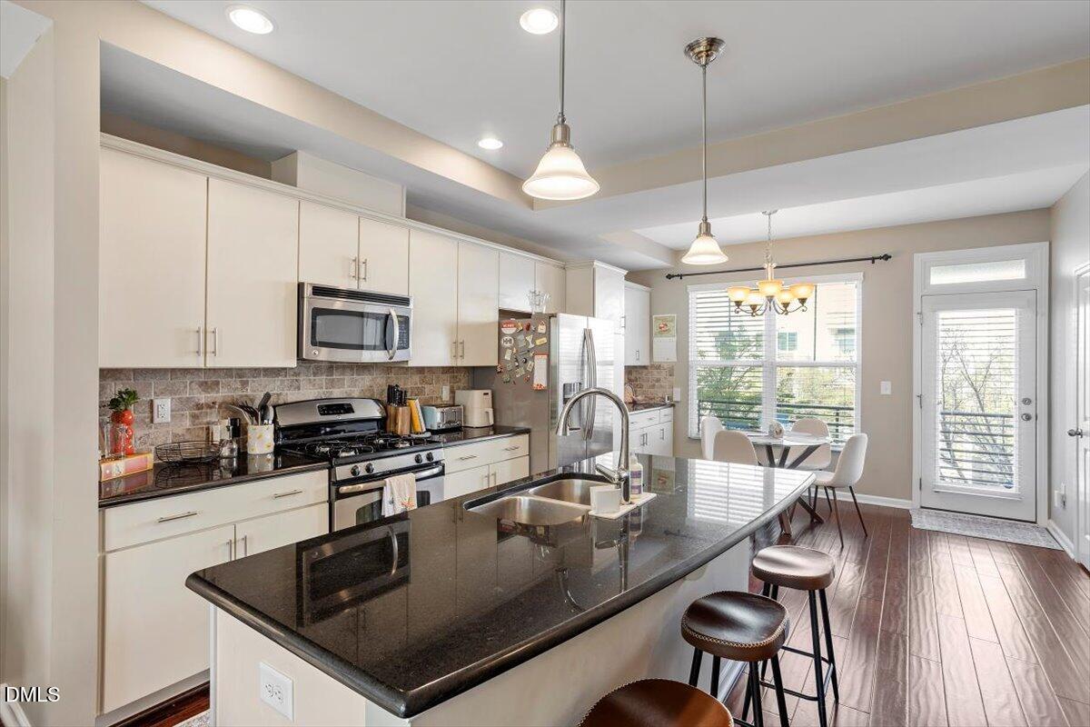 1427 Crafton Way Raleigh, NC 27607 - Photo 6 of 26 a kitchen with kitchen island granite countertop a sink a counter space appliances and cabinets