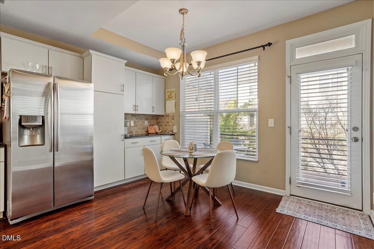 1427 Crafton Way Raleigh, NC 27607 - Photo 10 of 26 a dining room with wooden floor a chandelier a glass table and chairs