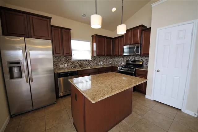 a kitchen with stainless steel appliances granite countertop a sink a refrigerator and a stove