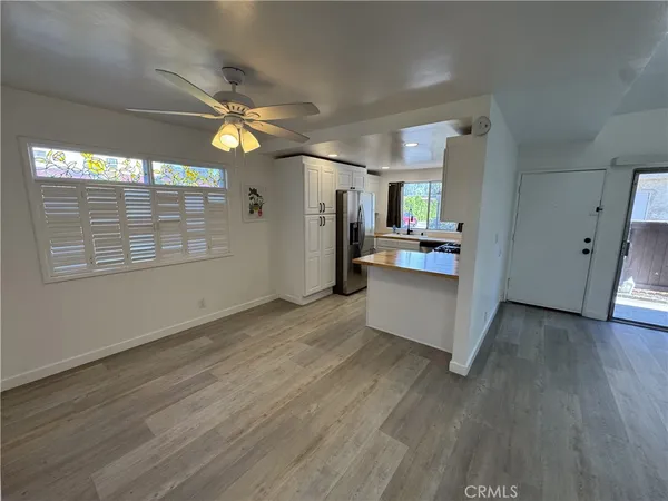 an empty room with wooden floor cabinet and windows