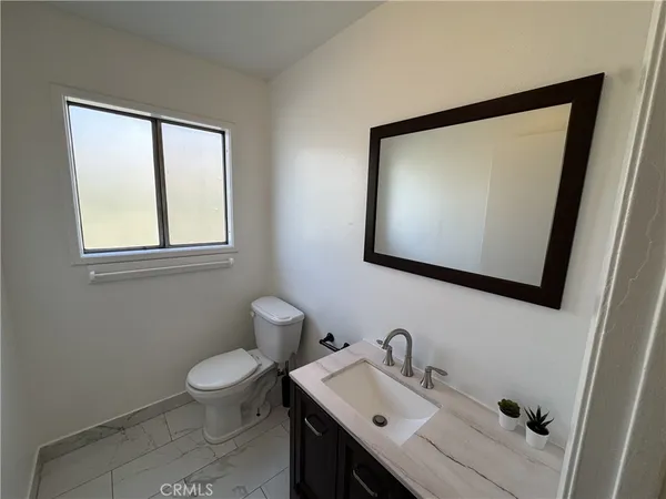 a bathroom with a toilet sink vanity and mirror