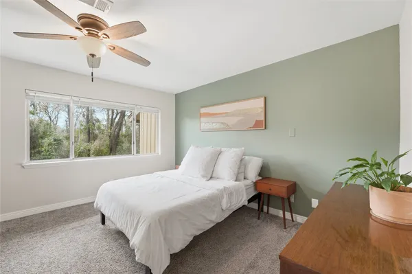 a bedroom with a bed chandelier and a window
