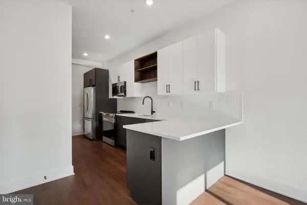 a large white kitchen with stainless steel appliances a refrigerator and a sink