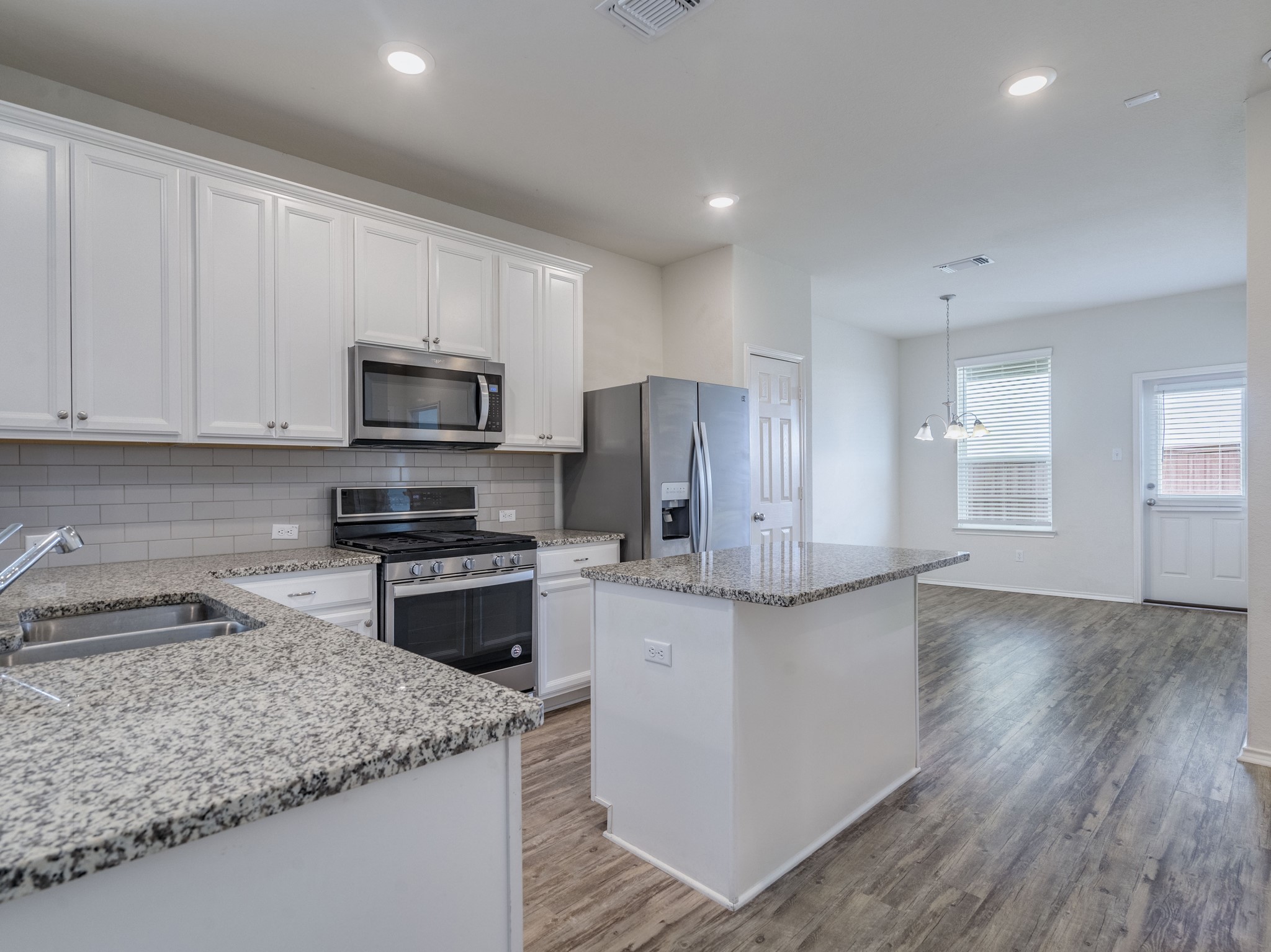 790 Pepperbark Loop Buda, TX 78610 - Photo 5 of 22 A well-appointed kitchen showcasing elegant granite countertops and modern appliances.