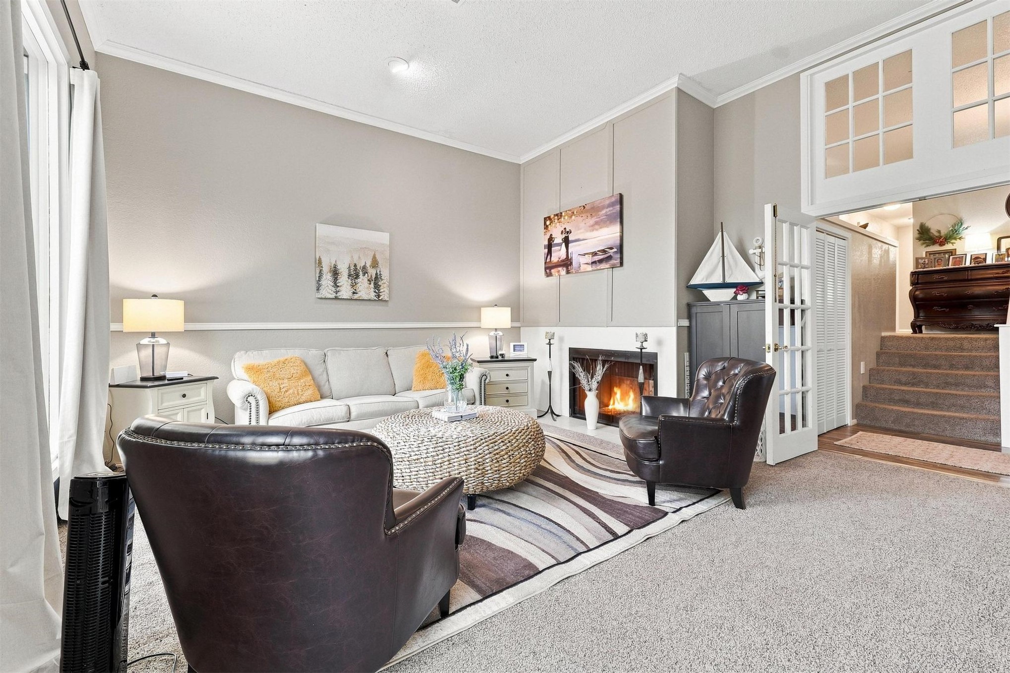 Living area with a fireplace, high ceilings, carpet flooring, and a half-paneled wall accent