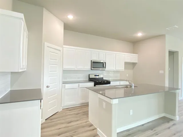 a view of kitchen with kitchen island granite countertop stainless steel appliances refrigerator sink and cabinets