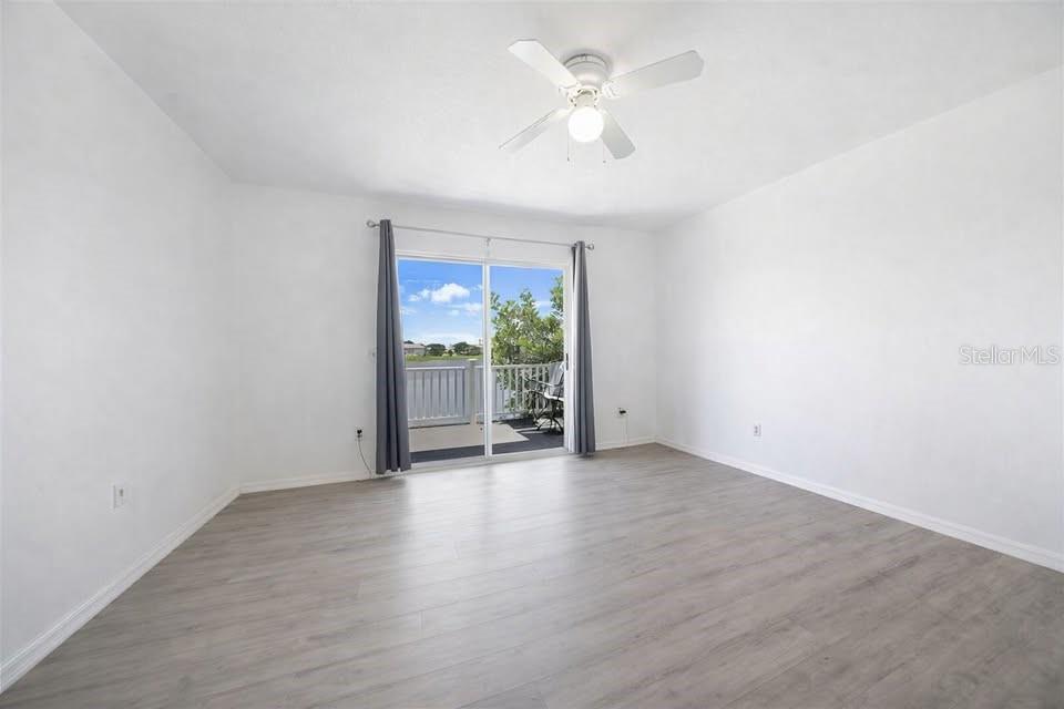 26272 Rampart Boulevard, Unit 107 Punta Gorda, FL 33983 - Photo 16 of 18 an empty room with wooden floor fan and windows